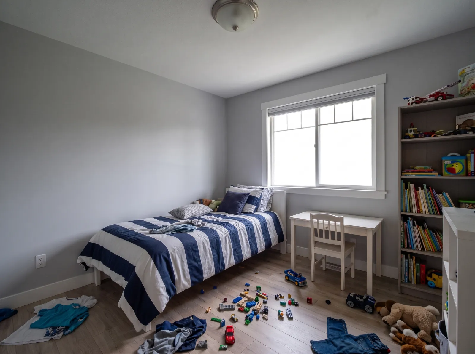 Kids' bedroom straight off the phone: blown window, flat grey light, toys on floor