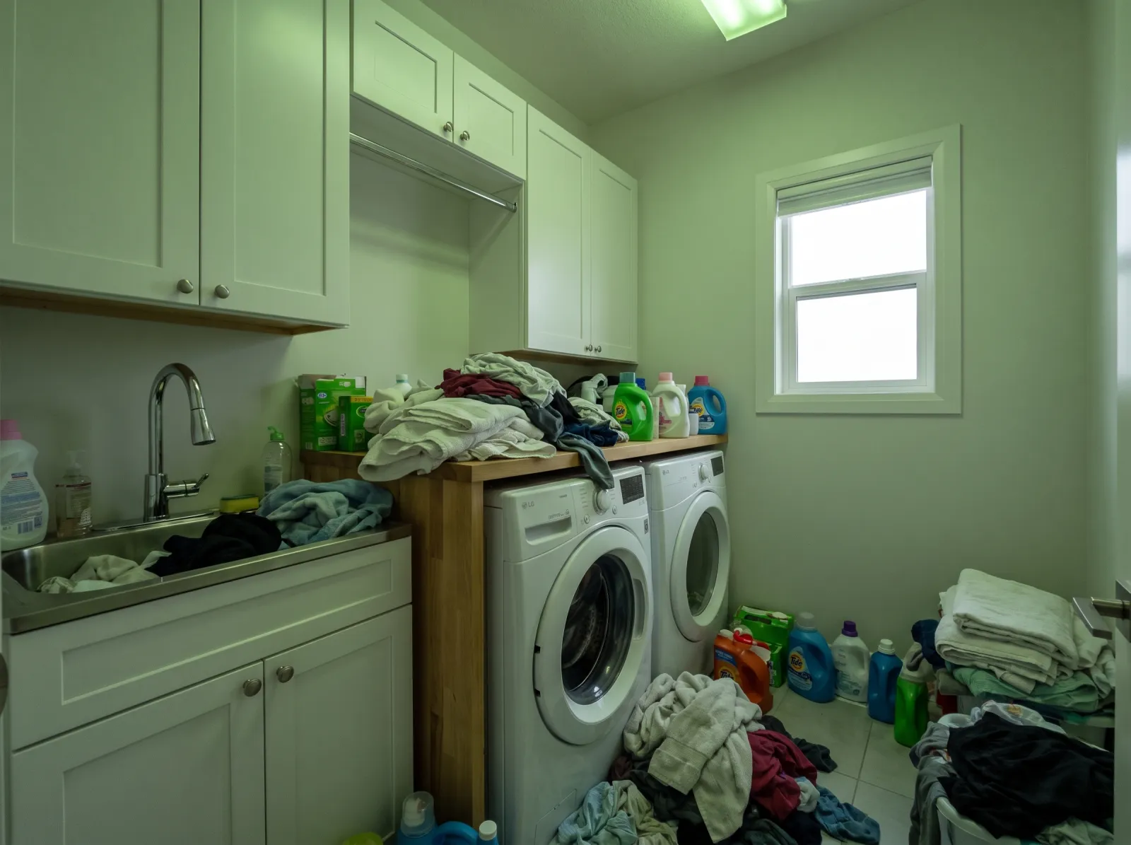 Laundry room straight off the phone: green fluorescent cast, laundry piles